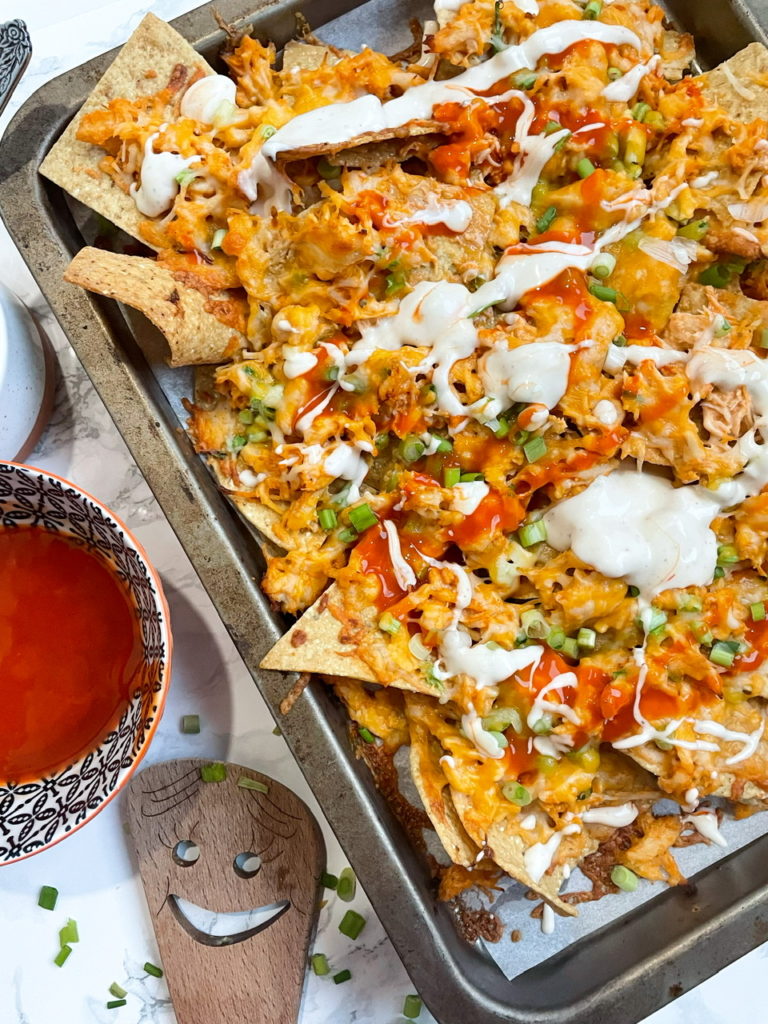 Buffalo Chicken Nachos with buffalo chicken, ranch dressing, and cheese