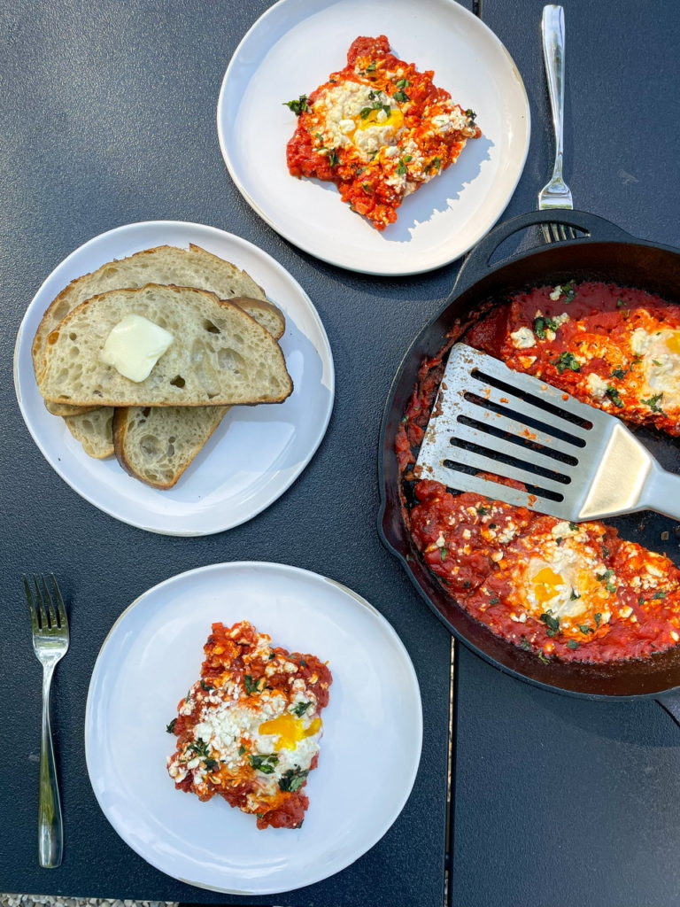 shakshuka with feta cheese made in a cast iron pan. served with toasted sourdough bread