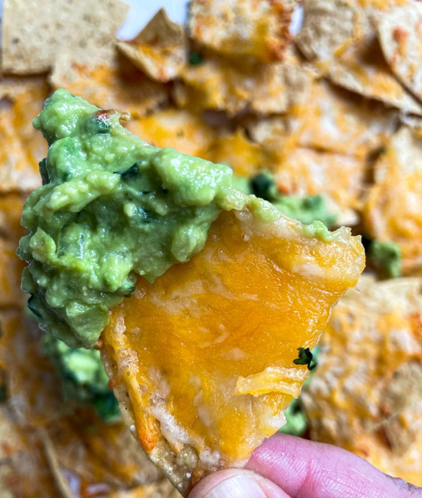 A close up photo of a tortilla cheese with melted cheese and guacamole 