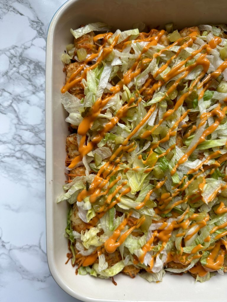 Big Mac Casserole topped with Tater Tots, Shredded Lettuce, Pickles, and Thousand Island Dressing
