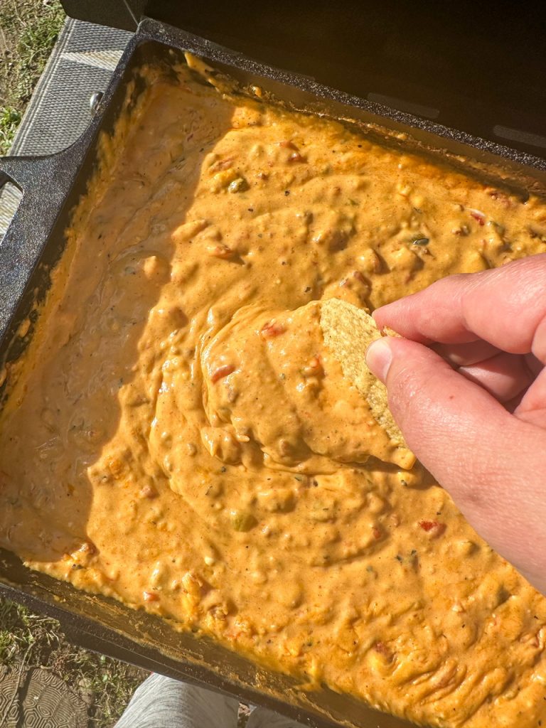 tortilla chip being dipped into queso with chorizo