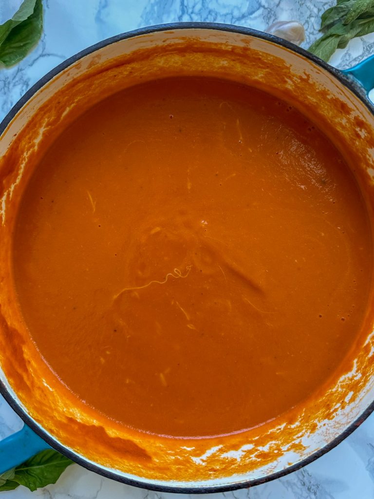 A big pot of tomato soup with melted parmesan cheese