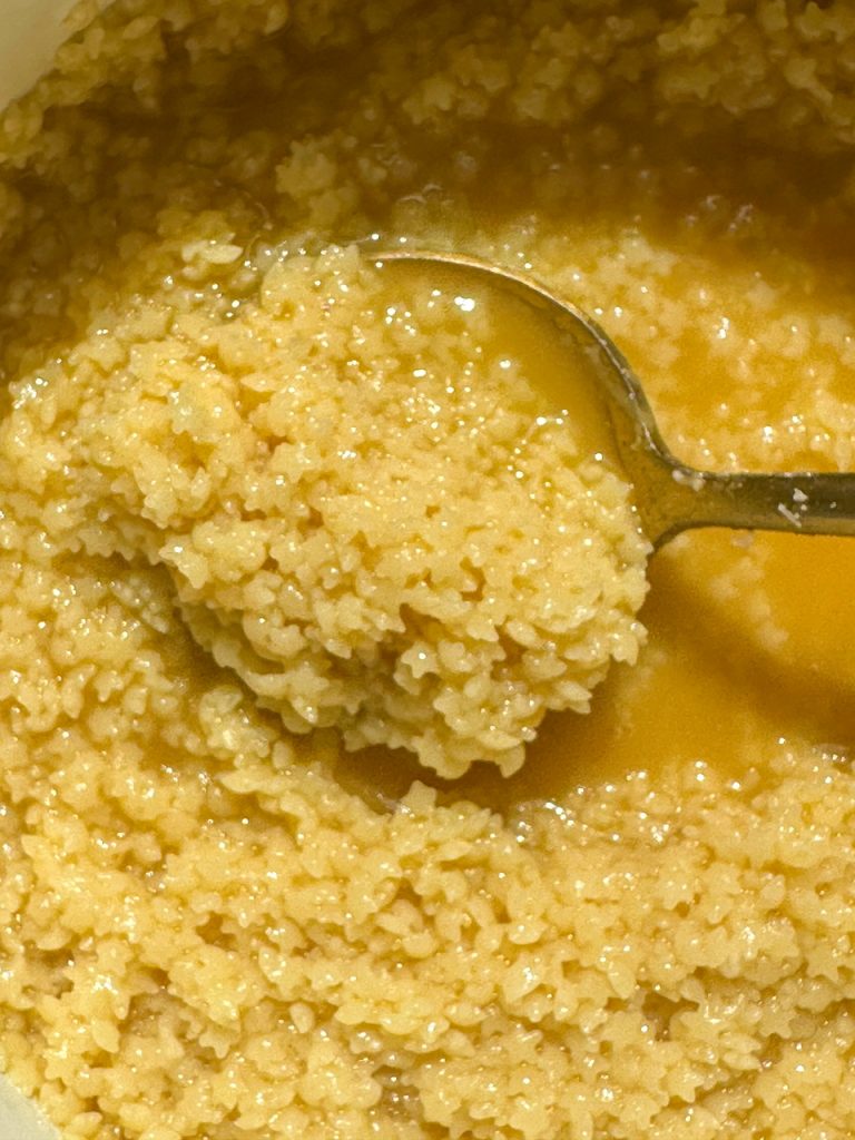 A close up of pastina cooked in chicken bone broth, butter, and pecorino cheese