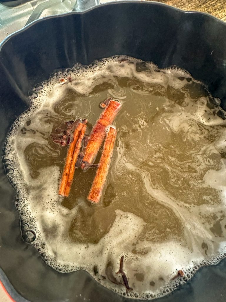 During the boiling process while making apple cider syrup using apple cider, cinnamon sticks, and cloves.