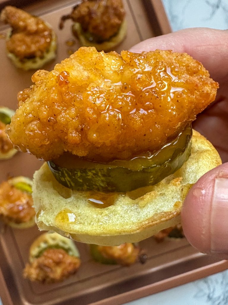 Chicken and waffle bites using frozen chicken nuggets and frozen mini waffles. Pickles are added to it as well as some hot honey. 