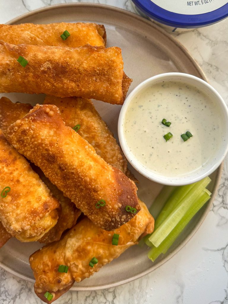 Buffalo Chicken Egg Rolls on a plate served with celery and ranch dressing