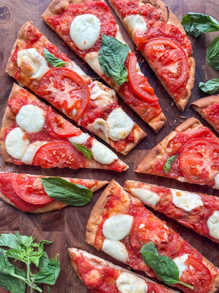 Easy margherita flatbread has fresh mozzarella, crushed tomatoes, sliced tomatoes, garlic, and fresh basil